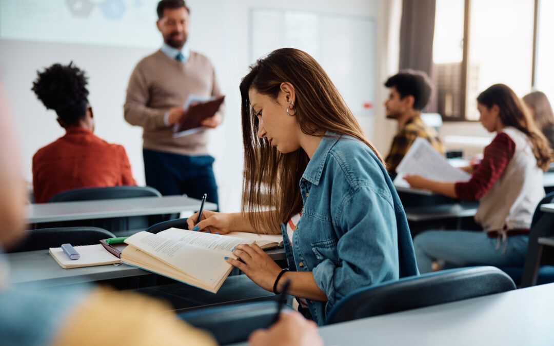 University student writing in her notebook while attending a lecture in the classroom.